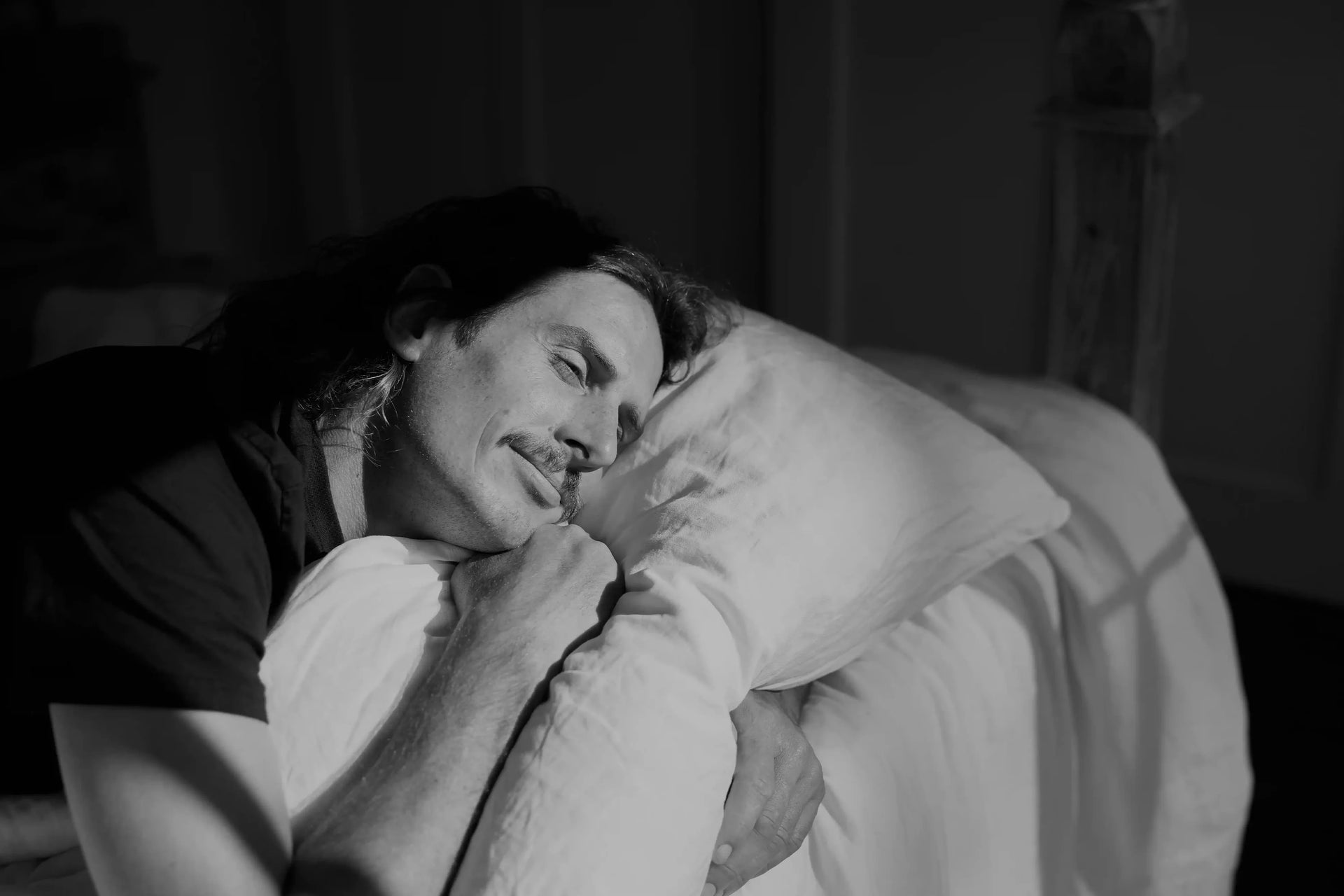 Person lying on a bed with a pillow, black and white photo